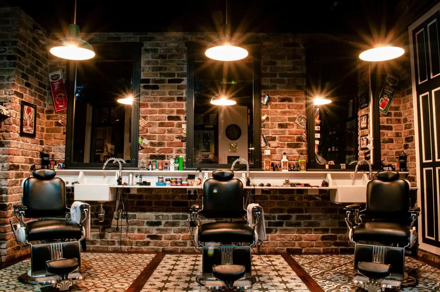 Interior de uma barbearia com cadeiras de barbeiro, espelhos e paredes de tijolo
