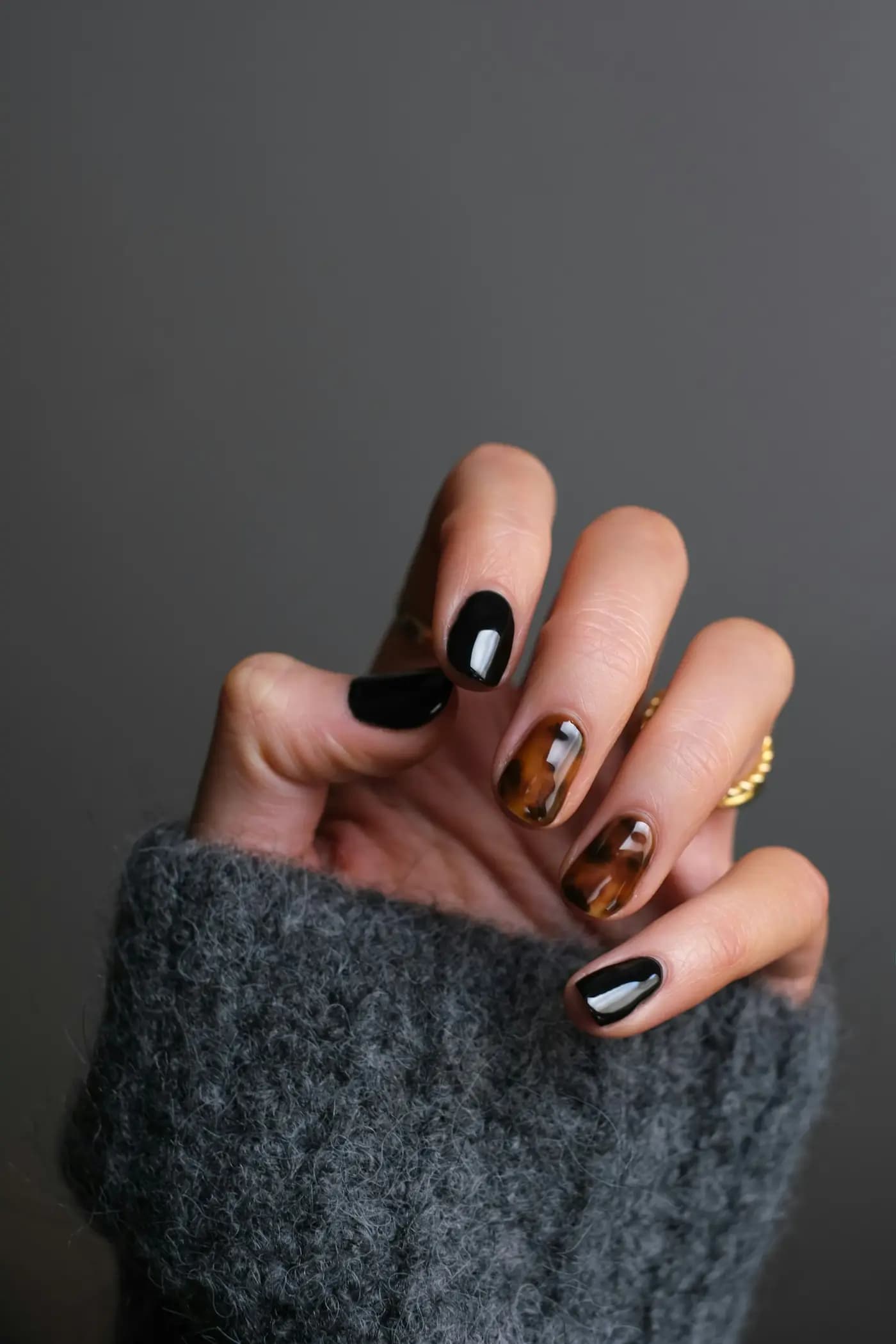 Mão com unhas de gel pintadas em preto e tartaruga